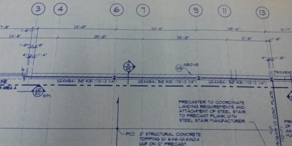 Section of a detailed architectural blueprint showing beam placements and measurements.