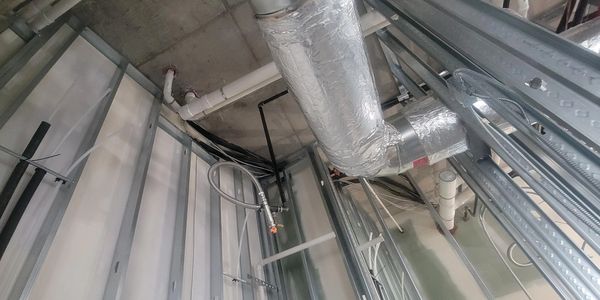 Exposed HVAC ducts and metal framing in an unfinished ceiling space.