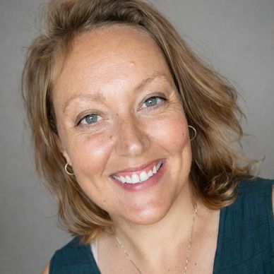 Smiling woman with light brown hair and blue eyes.
