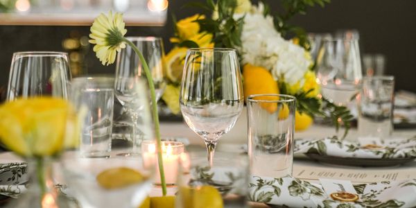 Elegant table setting with wine glasses, floral napkins, and yellow flowers.