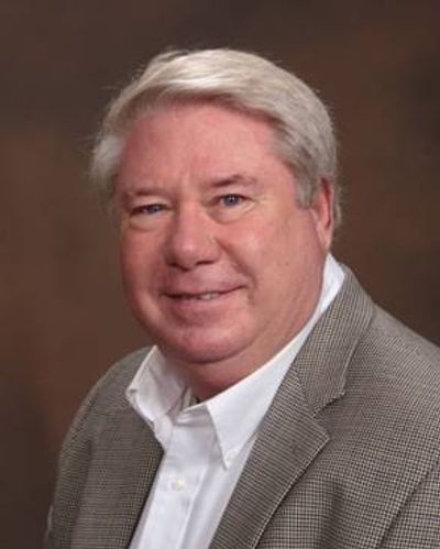 A portrait of a man wearing a neutral-colored outfit