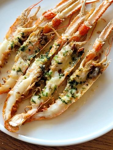Grilled shrimp with herbs on a white plate.