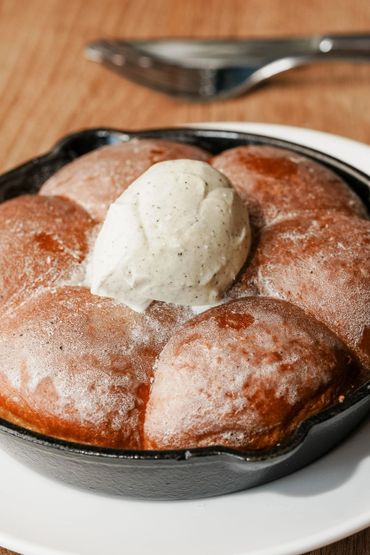 Warm cinnamon rolls with vanilla ice cream in a cast iron skillet.
