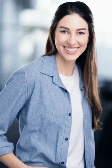Smiling young woman with long brown hair in casual blue shirt.