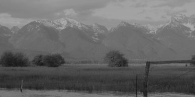 Black and white landscape of mountains and fields.