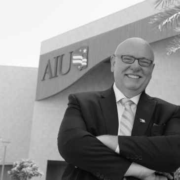 Smiling man in suit standing outside AIU building.