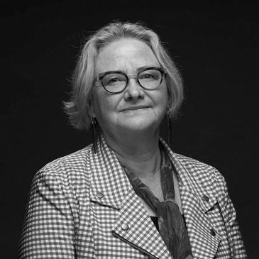 Black and white portrait of an elderly woman wearing glasses and a checkered jacket.