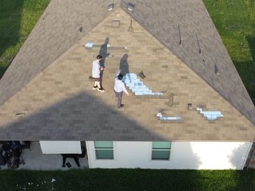 Two people working on a rooftop with scattered materials on a sunny day.