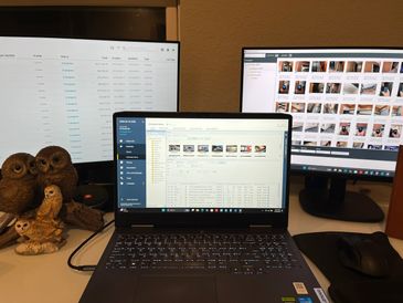A workspace with a laptop and two monitors displaying data and images.