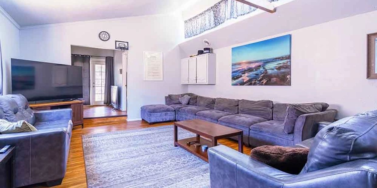 Spacious living room with large gray sofas and a wooden coffee table.