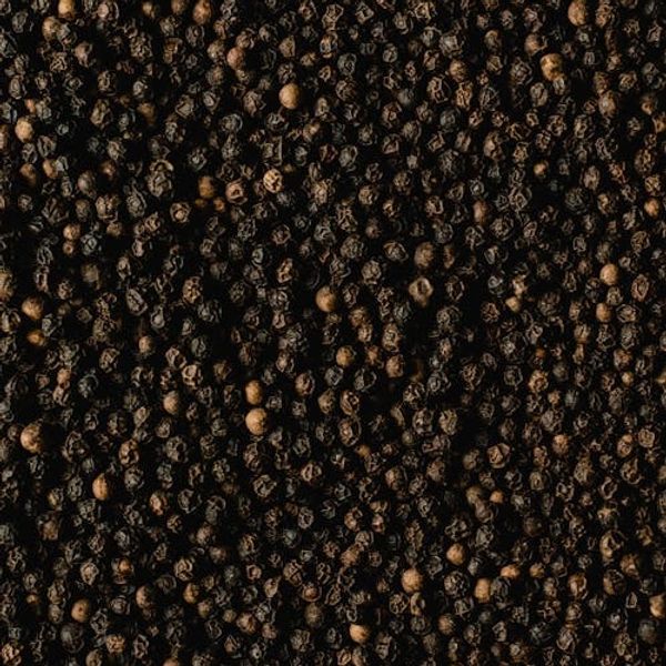 Close-up of numerous black peppercorns densely packed together.