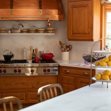 Cozy kitchen with wooden cabinets, stainless stove, and marble countertops.