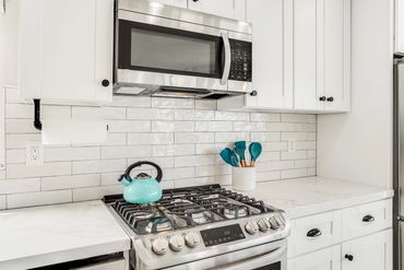 Modern kitchen with stainless steel stove and turquoise utensils.
