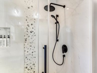 Modern shower with black fixtures and pebble tile accent wall.
