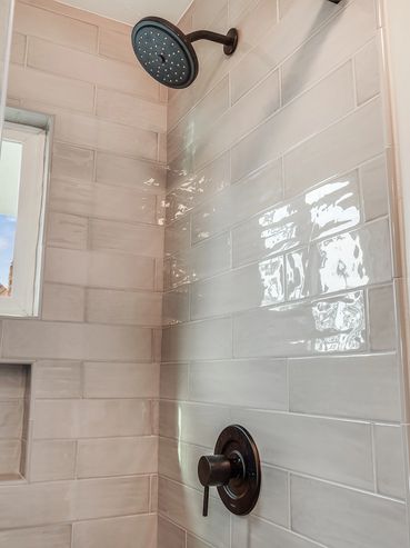Modern shower with beige tiles, rain showerhead, and labeled shampoo bottles.