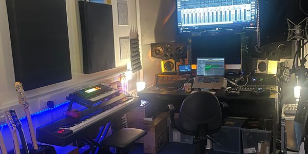 A cozy music production studio with keyboards, speakers, and a laptop on a desk - Production Room.
