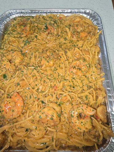 Tray of creamy shrimp pasta garnished with herbs.