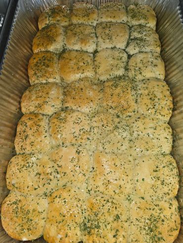 Freshly baked garlic herb dinner rolls in a foil tray.