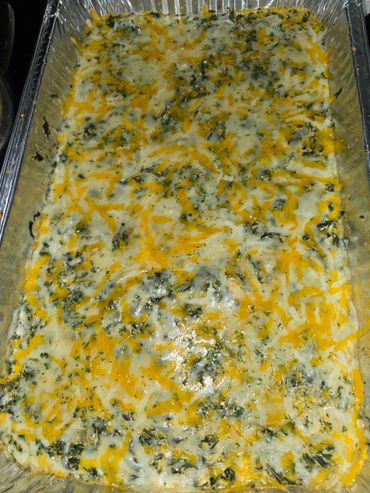 Baked cheesy spinach dip in a foil tray.