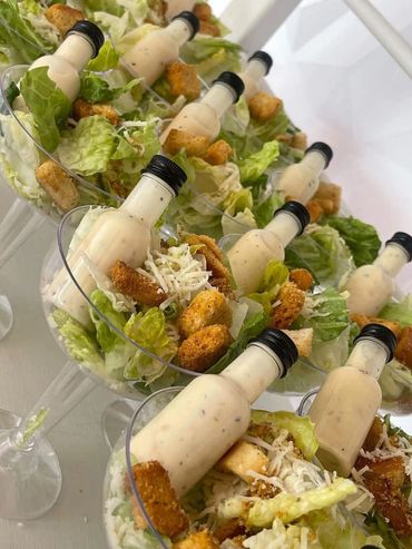 Individual Caesar salads served in clear glasses with small dressing bottles.
