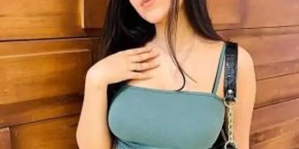 Young woman posing against a wooden wall with a black purse.