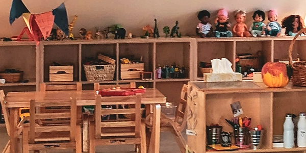 A cozy children's playroom with wooden furniture and toys on shelves.