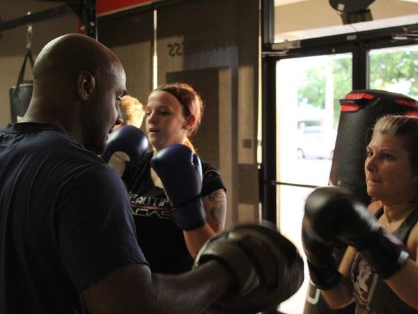 Boxing coach training two women in a gym.
