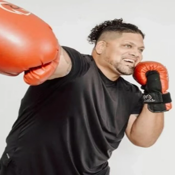 Personal trainer in boxing gloves throws punch with power and precision, showcasing combat technique