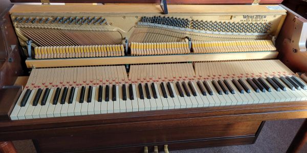 Open upright piano showing keys and internal mechanics.