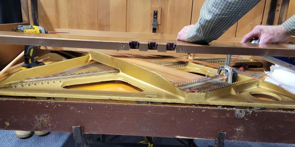 Hands repairing or tuning an old piano.