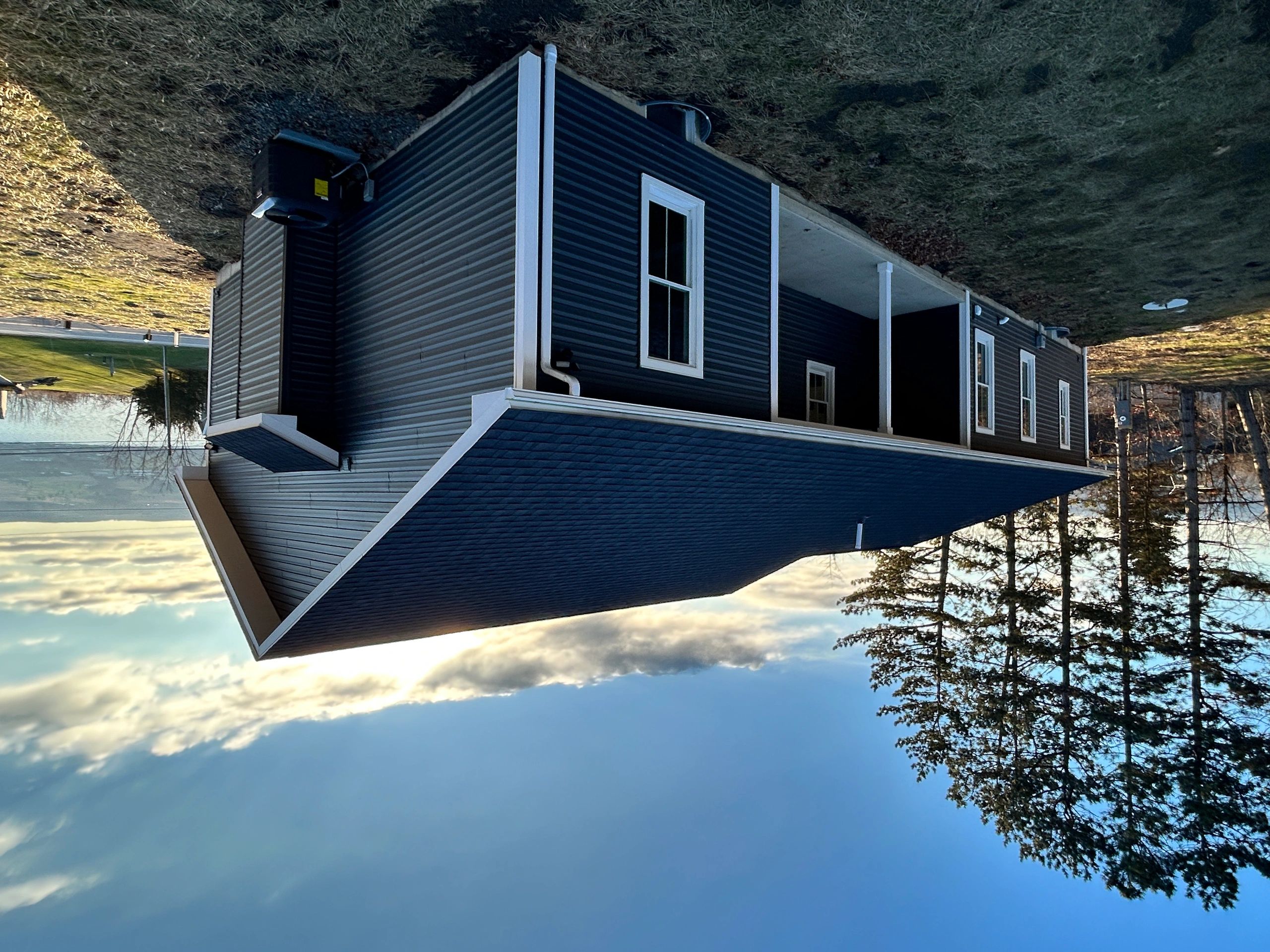 Modern black house with white trim under a clear sky.