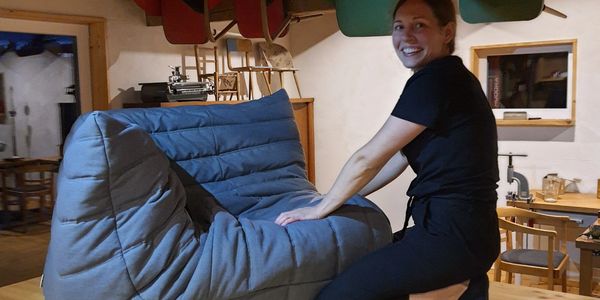 Frau freut sich über einen modern gepolsterten Sessel.