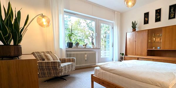 Gemütliches Schlafzimmer mit viel Holz und großen Fenstern.