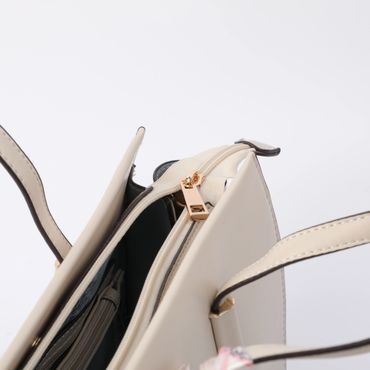 Close-up of a beige handbag with a zipper and handles.