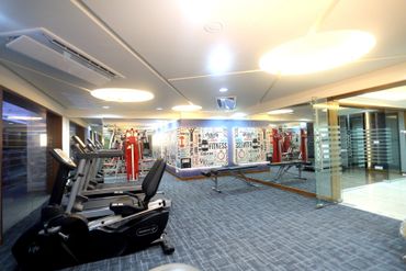 Modern gym with exercise bikes and weight machines under bright lighting.
