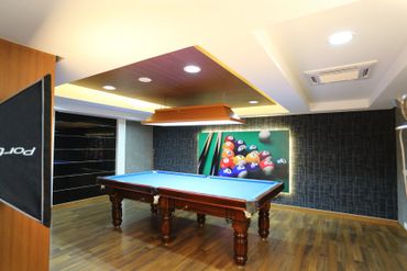 Modern indoor pool table room with wooden floor and stylish lighting.