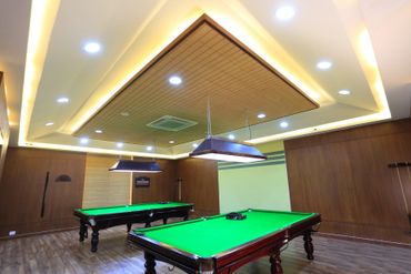 Modern indoor room with two snooker tables under recessed ceiling lights.