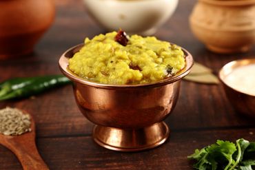 Traditional Indian dal served in a copper bowl with spices around.