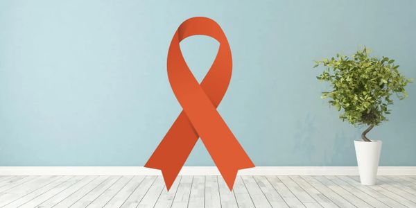 Large orange awareness ribbon on blue wall with potted plant.