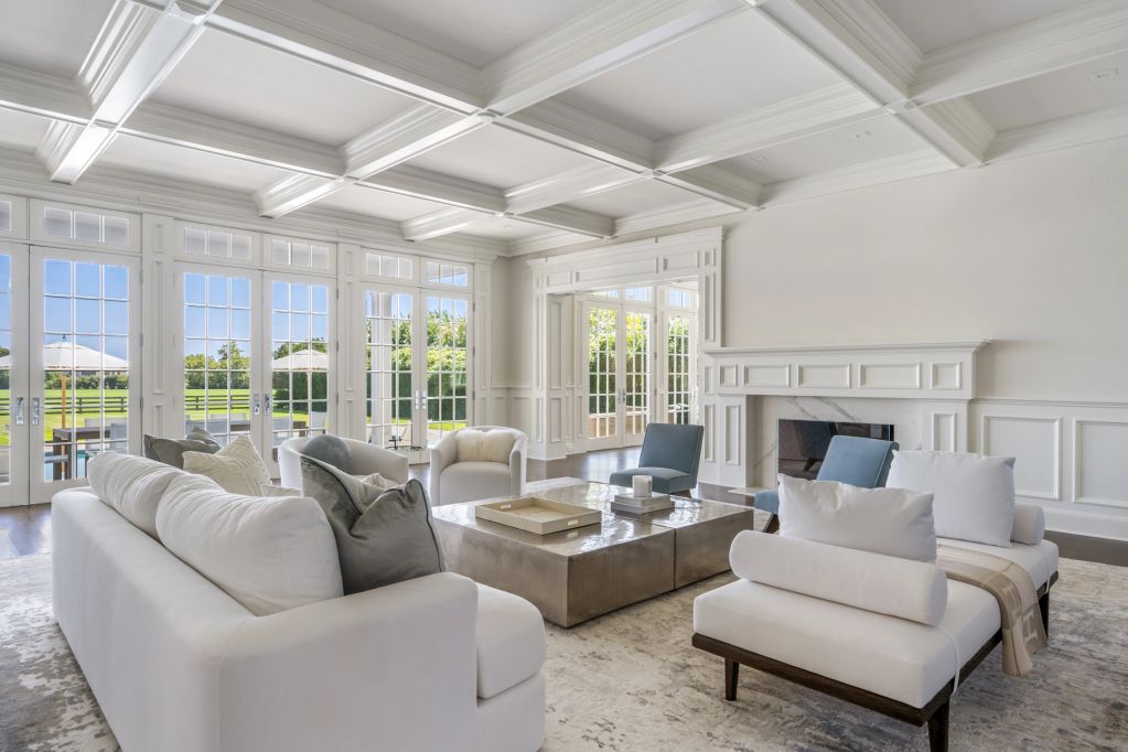Bright modern living room with white furniture and large windows.