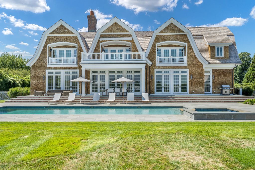 Large luxury house with a swimming pool and sun loungers.