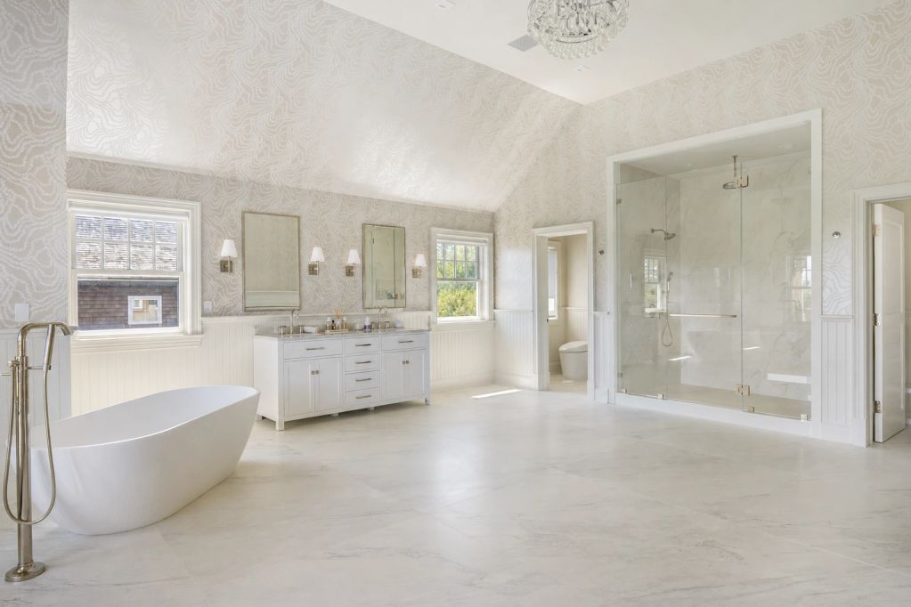Spacious modern bathroom with freestanding tub and large glass shower.