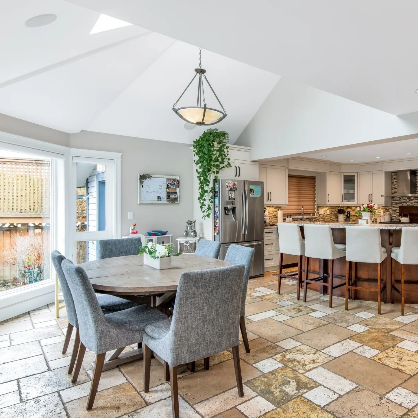 Modern kitchen and dining area with tiled floor and vaulted ceiling.
