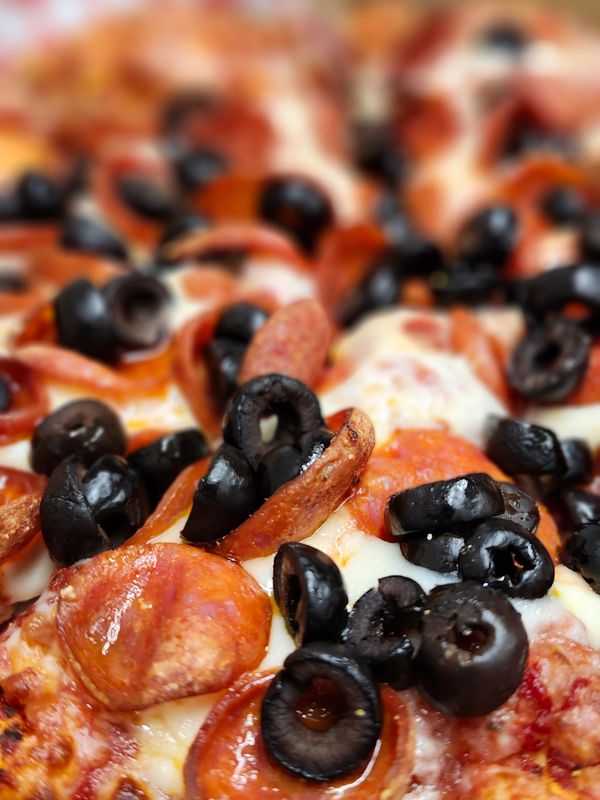 Close-up of pepperoni and black olive pizza with melted cheese.