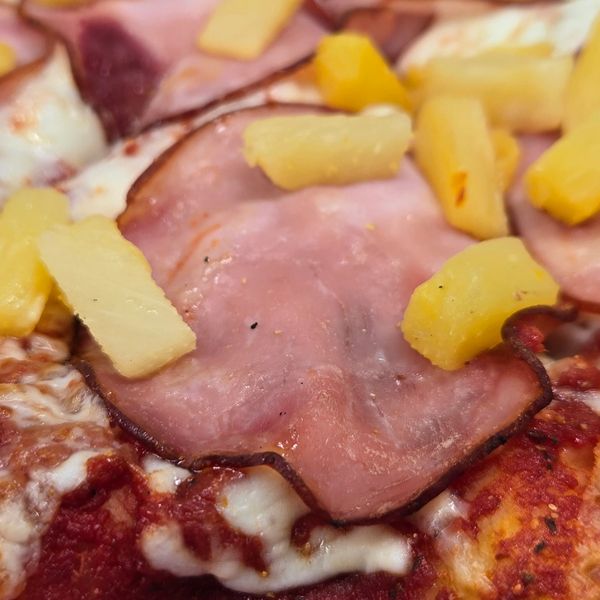 Close-up of ham and pineapple on a pizza.
