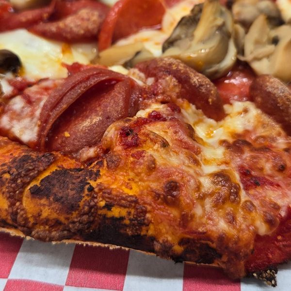 Close-up of a pepperoni and mushroom pizza slice with a crispy crust.