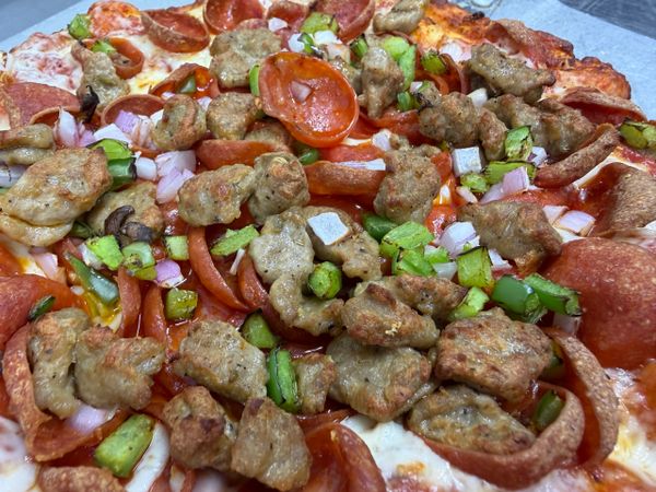 Close-up of a pizza topped with sausage, pepperoni, green peppers, onions, and mushrooms.