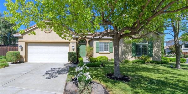 Single-story suburban house with a green front door and large tree in the yard.