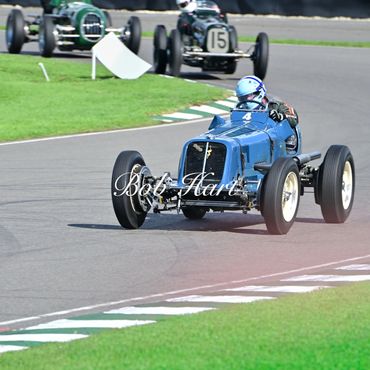 Blue classic racing car rounding bend at Goodwood Revival