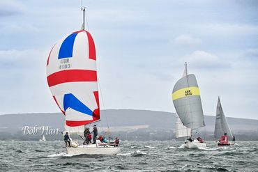 Sailboats racing on a choppy sea under cloudy skies.